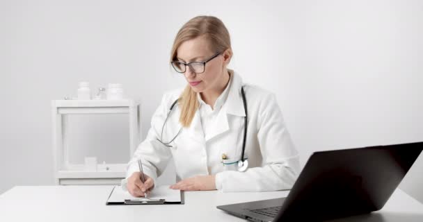 Medical worker sitting at office and doing paperwork — Stock Video