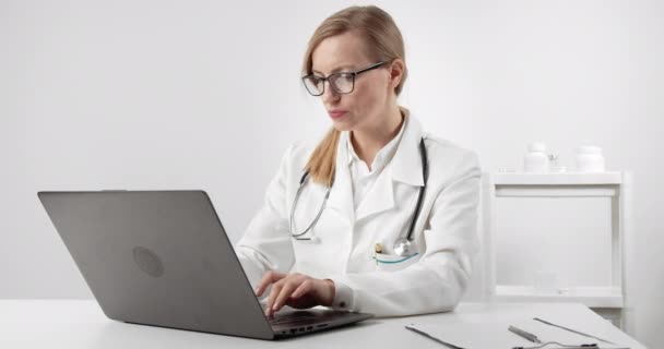 Donna matura in uniforme medica che lavora su laptop — Video Stock