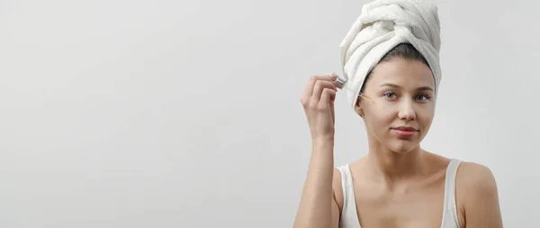 Jovem aplicando soro cosmético — Fotografia de Stock