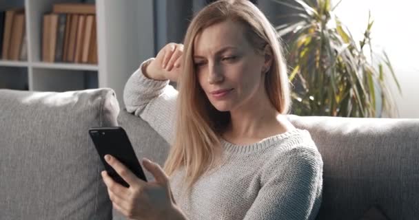 Mujer sonriente usando teléfono inteligente durante el tiempo libre — Vídeos de Stock