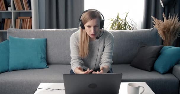Kulaklık takmış yetişkin bir kadın laptopta video konferansı yapıyor. — Stok video