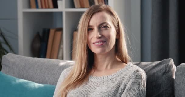 Retrato de la señora madura sentada en el sofá y sonriendo — Vídeos de Stock