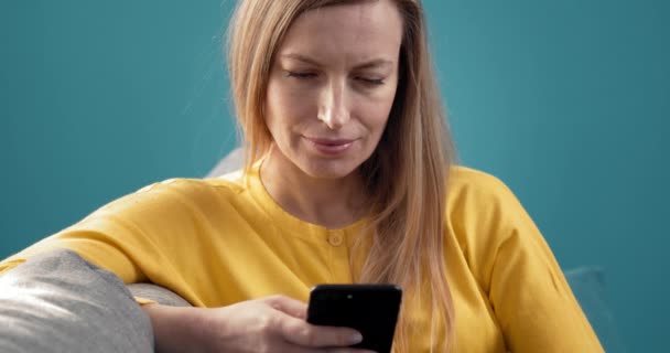 Retrato de mulher encantadora relaxante no sofá com smartphone — Vídeo de Stock