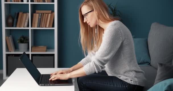 Evde dizüstü bilgisayarda çalışan olgun bir kadının yan görüntüsü — Stok video
