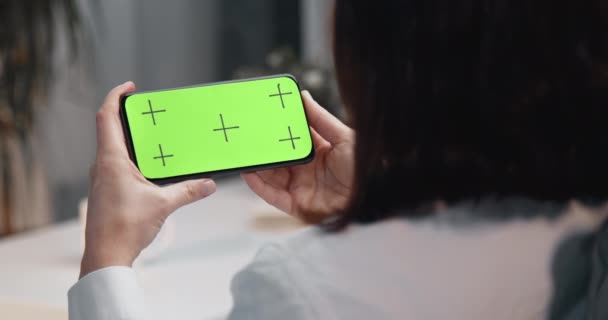 Вид сзади женщины, держащей телефон с хромаковым экраном — стоковое видео