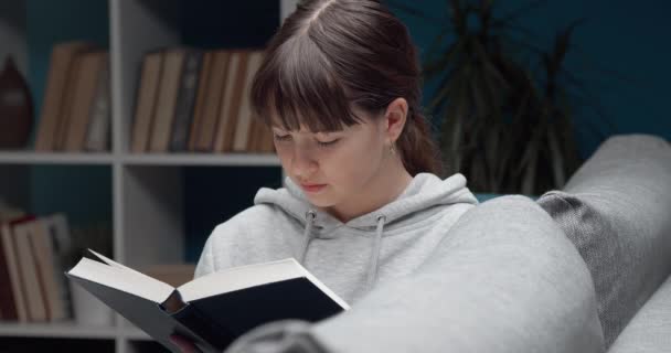 Mooi meisje lezen interessant boek thuis — Stockvideo