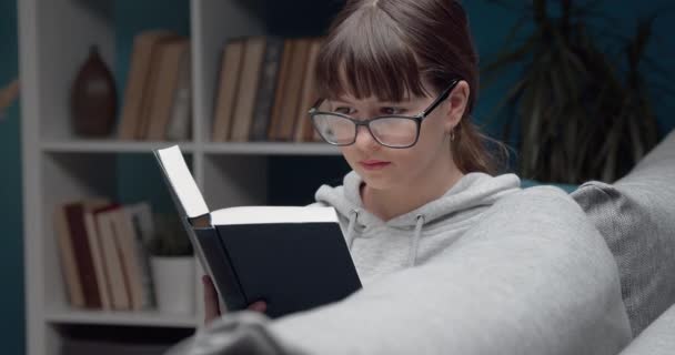 Vacker flicka läser bok under fritid hemma — Stockvideo