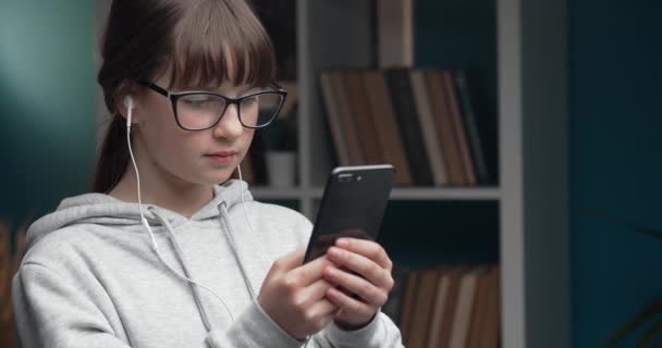 Aantrekkelijke tiener met behulp van smartphone tijdens het zitten op de bank — Stockvideo
