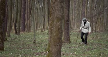 Olgun bir adam ormanda yürüyor ve yaşlı ağaçları keşfediyor.