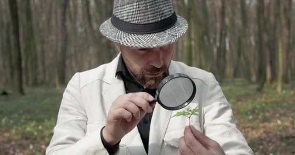 Γενειοφόρος άνθρωπος ανακαλύπτουν πράσινα φυτά με λούπα — Αρχείο Βίντεο