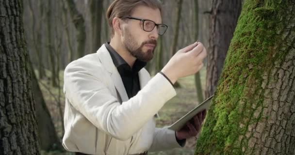 Botánico competente examinando musgo verde en el bosque — Vídeos de Stock