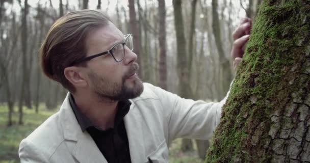 Побочный вид зрелого мужчины в очках, обнаруживающего зеленый мох — стоковое видео
