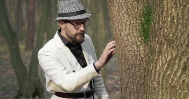 Retrato de homem barbudo examinando musgo verde na árvore velha — Vídeo de Stock