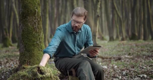 Botanicus met digitale tablet die groen mos onderzoekt — Stockvideo