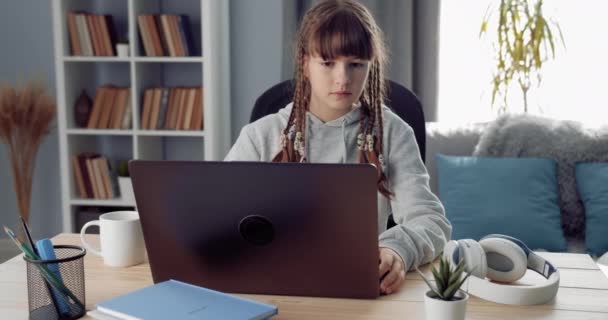 Ответственная школьница учится онлайн на ноутбуке — стоковое видео