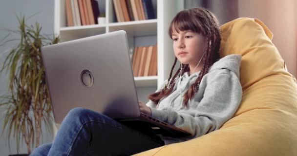 Χαριτωμένο κορίτσι που διαβάζει εξ αποστάσεως με φορητό υπολογιστή στο σπίτι — Αρχείο Βίντεο
