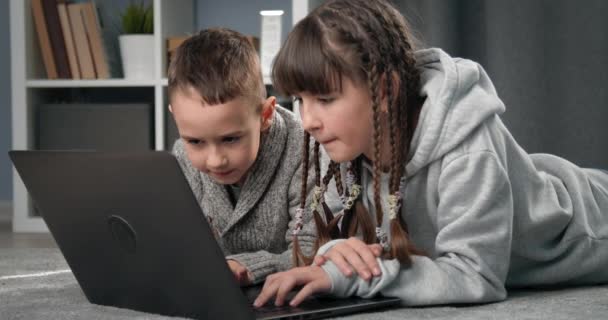 Grupa dwójki uśmiechniętych dzieci grających w gry na laptopie — Wideo stockowe