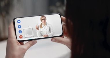 Kadın antiseptikle ilgili video izlemek için telefon kullanıyor.