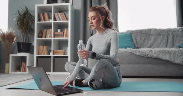 Sportig kvinna vilar efter träning med laptop och vatten — Stockvideo