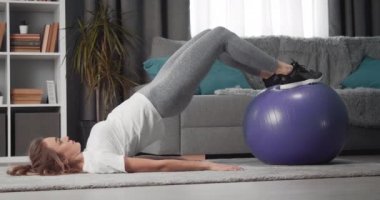 Güçlü kız fitness topunda bacak egzersizi yapıyor.