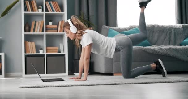 Flicka gör övningar medan du tittar på handledning på bärbar dator — Stockvideo