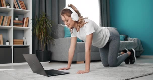 Active girl repeating exercises during online workout — Stock Video
