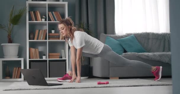 Mujer haciendo ejercicios de fitness en casa durante el tutorial en línea — Vídeos de Stock