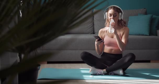 Mujer relajándose en esterilla de yoga después del entrenamiento con smartphone — Vídeos de Stock