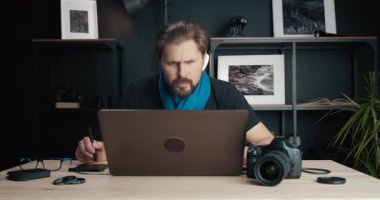 Sakallı fotoğrafçı stil kalemle fotoğrafları rötuşluyor.