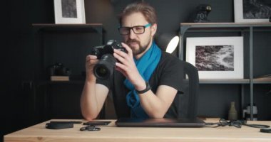 Olgun sakallı adam kamerada fotoğrafları kontrol ediyor.