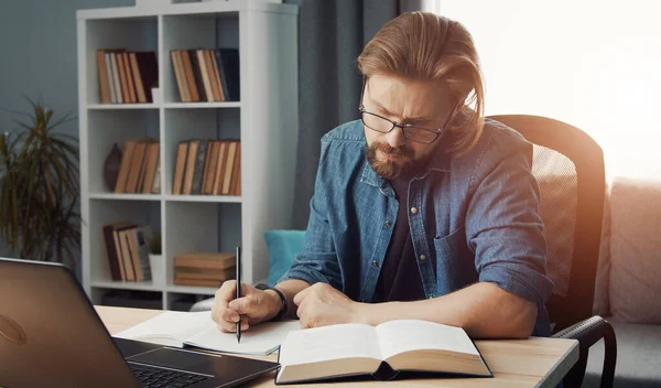 Чоловік дивиться книгу робить нотатки — стокове фото