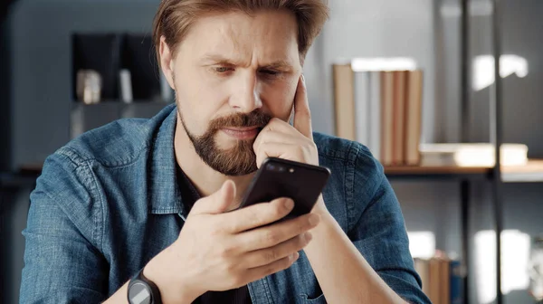 Hombre pensativo mirando la pantalla del teléfono inteligente —  Fotos de Stock