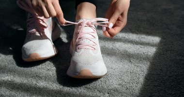 Spor ayakkabı bağlayan kadın elleri.