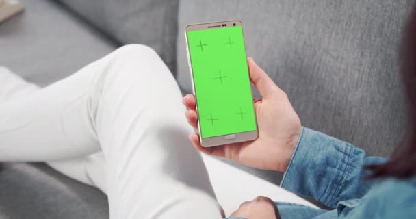 Achteraanzicht van vrouw met smartphone met groen scherm — Stockvideo
