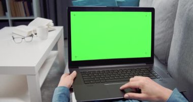 Kanepede dizüstü bilgisayarı açık olarak dinlenen genç bir kadın.