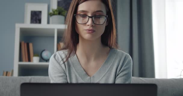 Nahaufnahme einer Frau, die auf der Couch sitzt und am Laptop arbeitet — Stockvideo