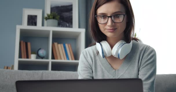 Gyönyörű lány dolgozik laptop, miközben ül a kanapén — Stock videók