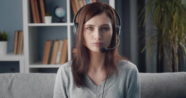 Hermosa mujer en auriculares hablando durante la videoconferencia — Vídeos de Stock