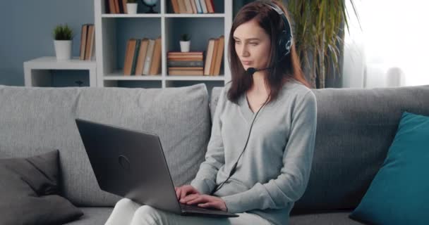 Aantrekkelijke vrouw in headset met behulp van laptop tijdens video chat — Stockvideo