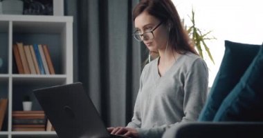 Mutlu kadın evde oturuyor ve kişisel laptopuyla çalışıyor.