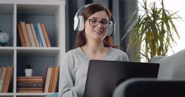 笑顔の女の子はノートパソコンでビデオ通話中に感情的に話している — ストック動画
