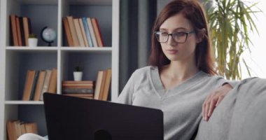 Düşünceli kadın evde bilgisayar ekranına bakıyor.