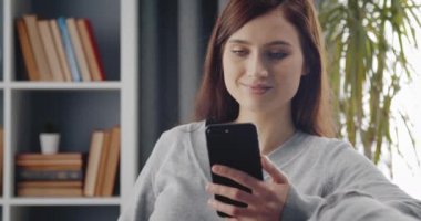 Boş zamanlarında modern akıllı telefon kullanan gülümseyen kız.