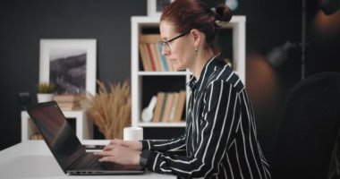 Uzaktan çalışma için kişisel dizüstü bilgisayar kullanan bir kadının yan görünümü