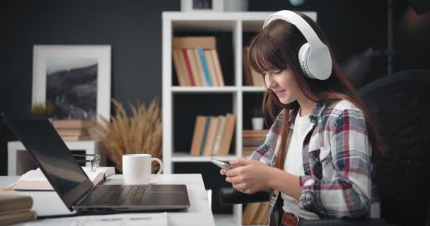 Glückliches Mädchen im Kopfhörer mit Smartphone zu Hause — Stockvideo