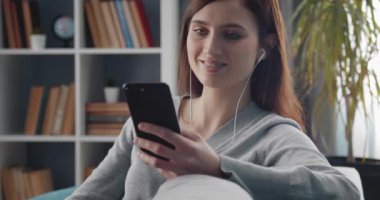 Akıllı telefondan müzik dinleyen genç bayanın portresi