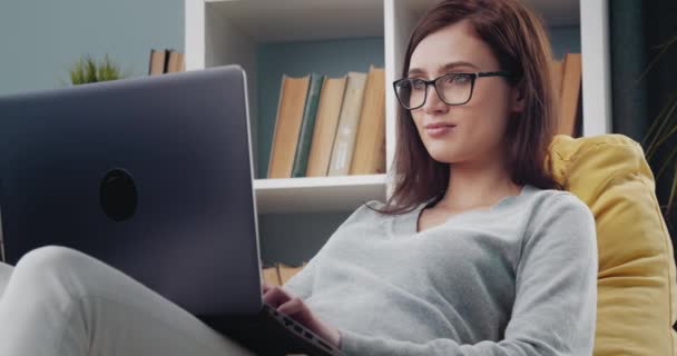 Frau arbeitet auf Laptop während sie auf Sitzsack-Stuhl sitzt — Stockvideo