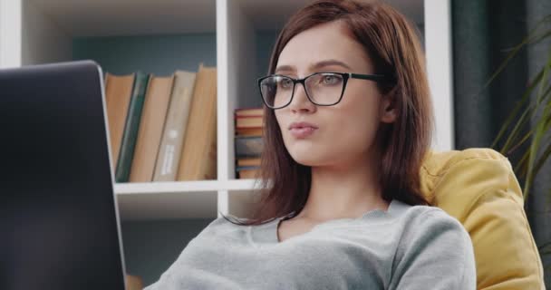 Nahaufnahme eines Mädchens mit Brille, das zu Hause am Laptop arbeitet — Stockvideo