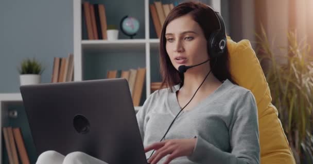 Vonzó nő headset dolgozik otthonról laptop — Stock videók