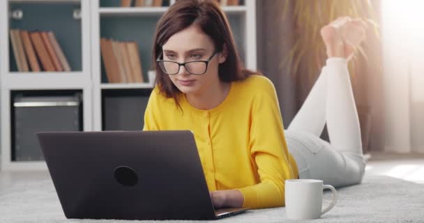 Концентрированная девушка, использующая ноутбук для удаленной работы дома — стоковое видео